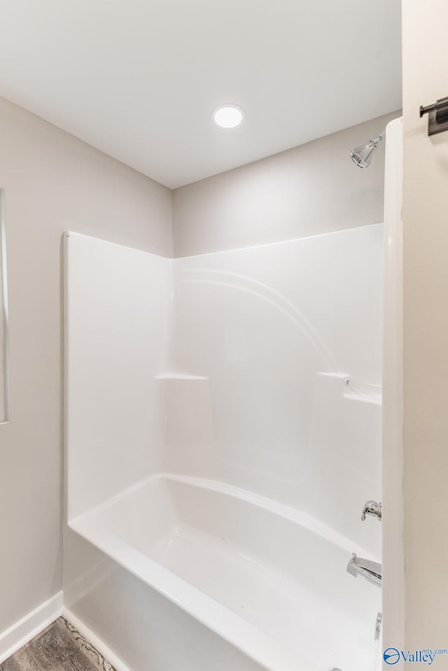 full bath featuring baseboards, wood finished floors, and tub / shower combination