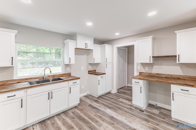 kitchen featuring butcher block counters, recessed lighting, white cabinetry, a sink, and light wood finished floors