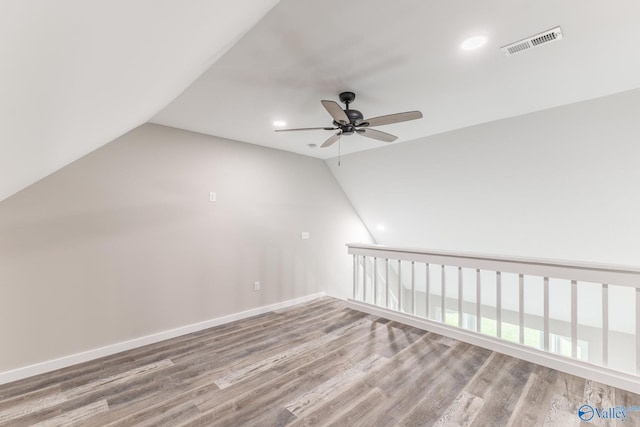 additional living space with ceiling fan, baseboards, wood finished floors, lofted ceiling, and visible vents
