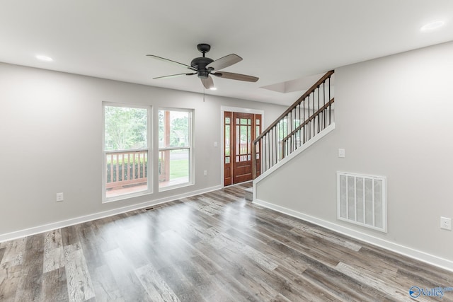 unfurnished living room featuring ceiling fan, stairs, baseboards, wood finished floors, and visible vents