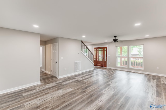 unfurnished living room featuring ceiling fan, visible vents, wood finished floors, stairway, and recessed lighting