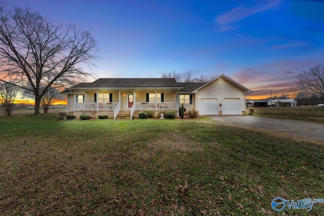 ranch-style home featuring a garage, a yard, and covered porch