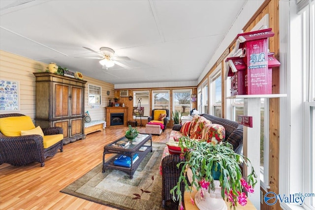 living room featuring hardwood / wood-style floors, wooden walls, and ceiling fan