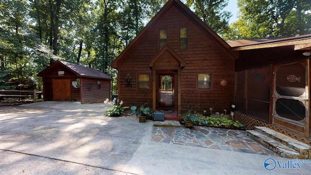 chalet / cabin with a storage shed, an outdoor structure, and a patio area