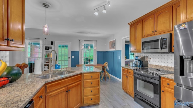2317 Little Cove Rd, Owens Cross Roads, AL 35763 - kitchen with appliances with stainless steel finishes, brown cabinets, a wainscoted wall, light stone countertops, and hanging light fixtures