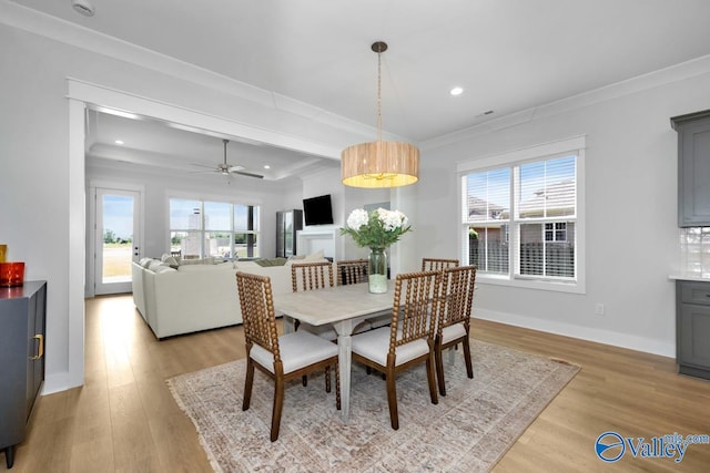 dining room featuring ornamental molding, light hardwood / wood-style flooring, ceiling fan, and a tray ceiling