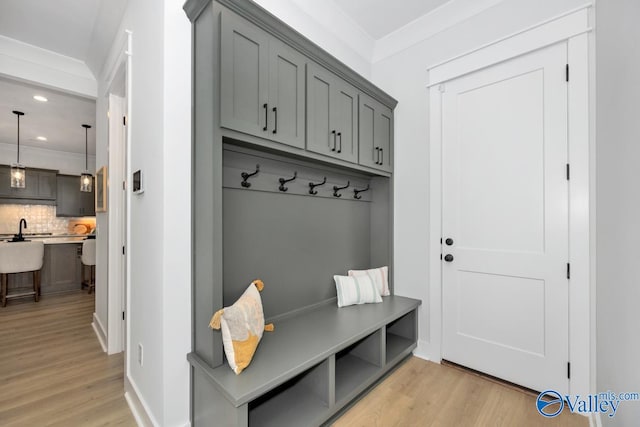 mudroom with light hardwood / wood-style floors, sink, and ornamental molding