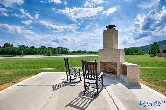 view of patio / terrace featuring a water view and an outdoor brick fireplace