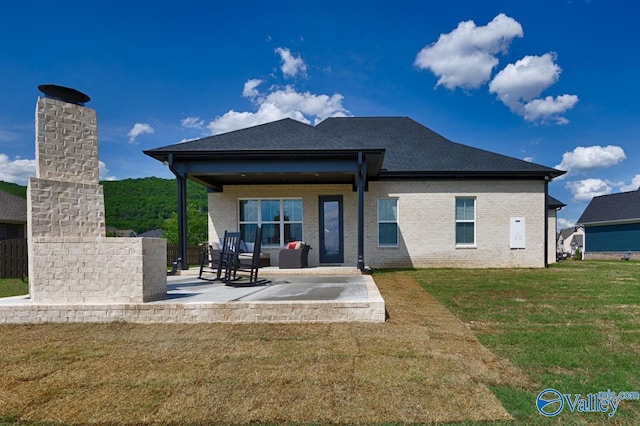 back of house featuring a fireplace, a patio area, and a lawn