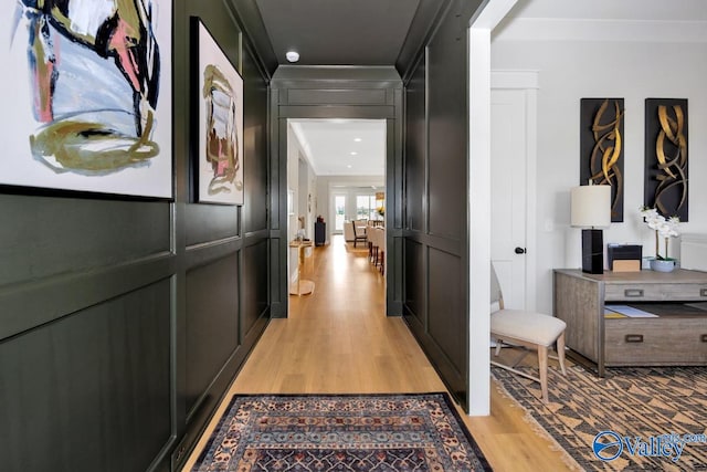 hallway with ornamental molding and light hardwood / wood-style floors