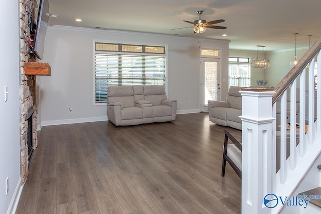 living room featuring dark wood-style flooring, a fireplace, ornamental molding, baseboards, and stairs