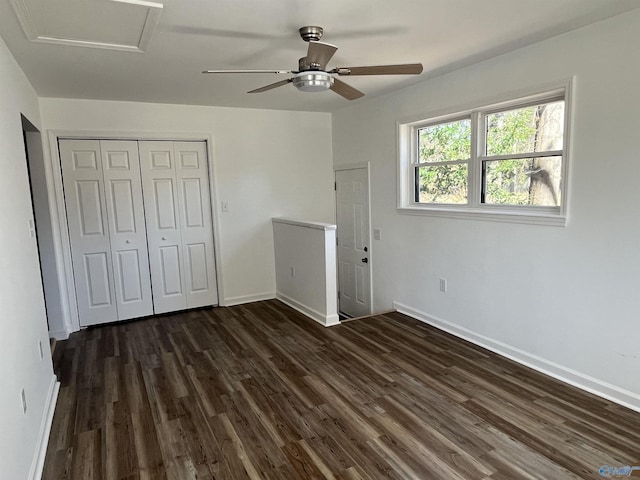 unfurnished bedroom with a ceiling fan, baseboards, a closet, dark wood finished floors, and attic access