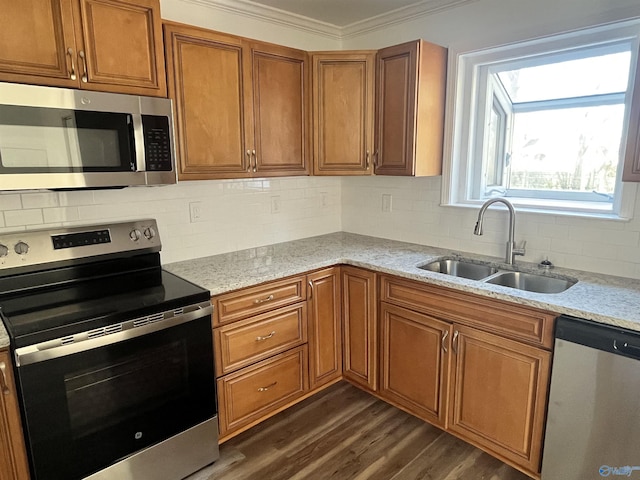 kitchen with brown cabinets, dark wood-style flooring, stainless steel appliances, crown molding, and a sink