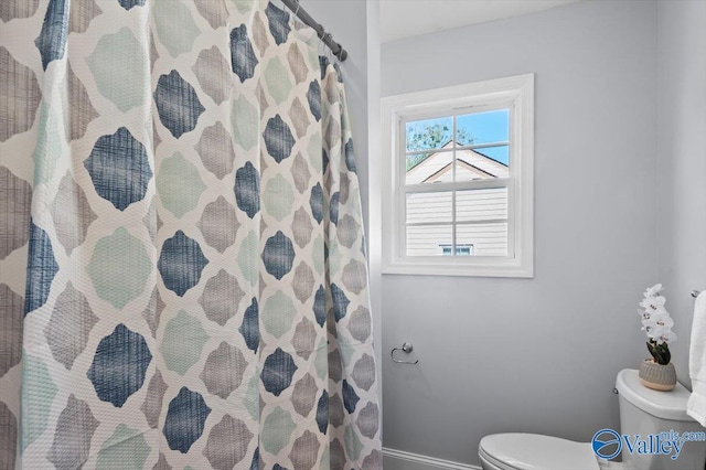 bathroom with curtained shower, toilet, and baseboards