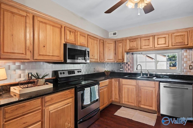 kitchen with tasteful backsplash, dark stone countertops, sink, dark hardwood / wood-style flooring, and appliances with stainless steel finishes