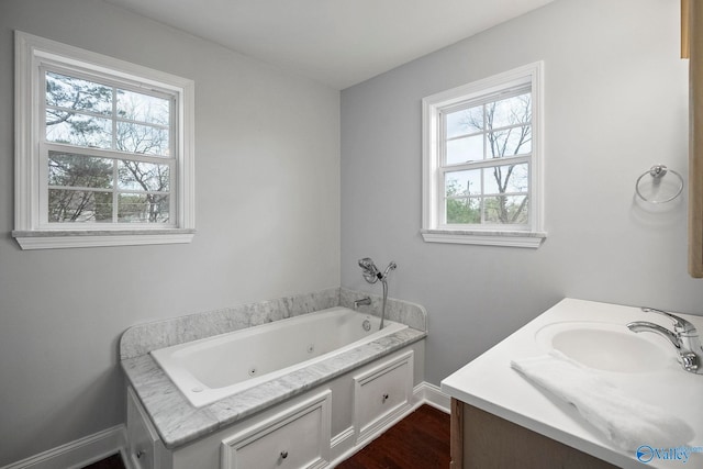 full bath featuring baseboards, vanity, wood finished floors, and a whirlpool tub