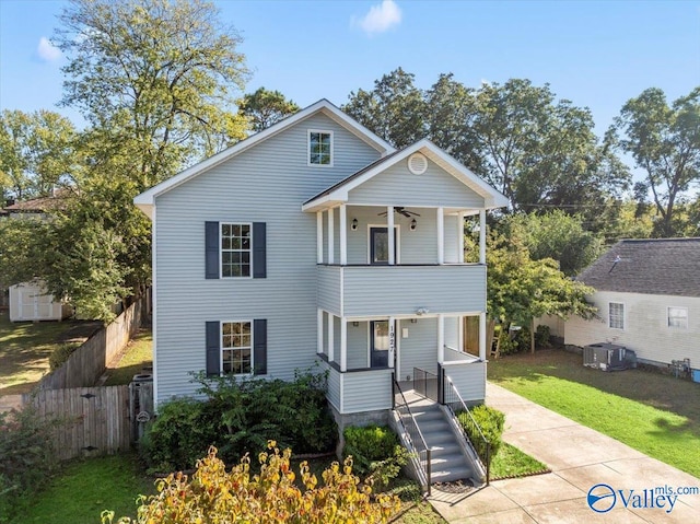 front of property with ceiling fan, a front yard, and a balcony