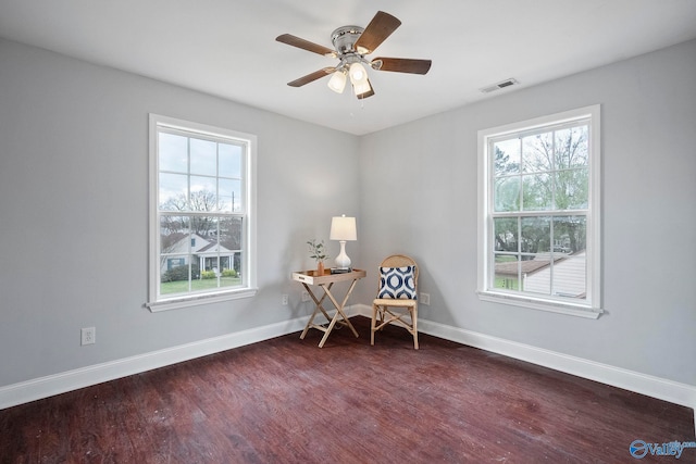 sitting room featuring baseboards, a wealth of natural light, visible vents, and dark wood-type flooring