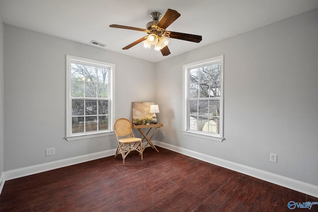 living area with a wealth of natural light, baseboards, visible vents, and wood finished floors