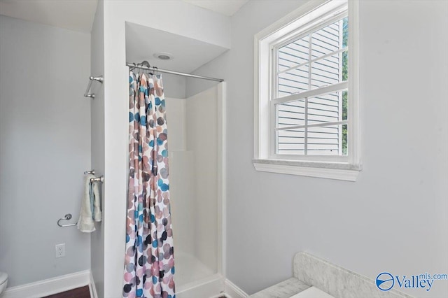 bathroom with plenty of natural light, a shower with shower curtain, and toilet