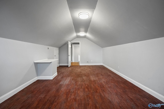 additional living space featuring baseboards, dark wood-style flooring, and lofted ceiling