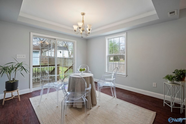 dining area featuring a notable chandelier, a tray ceiling, a wealth of natural light, ornamental molding, and wood finished floors