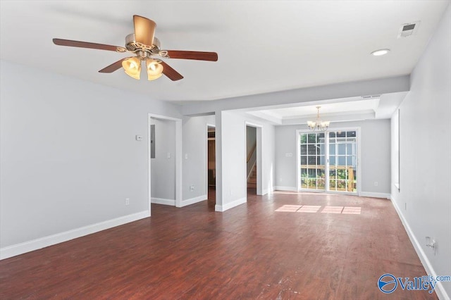 empty room with ceiling fan with notable chandelier, dark hardwood / wood-style floors, and a tray ceiling