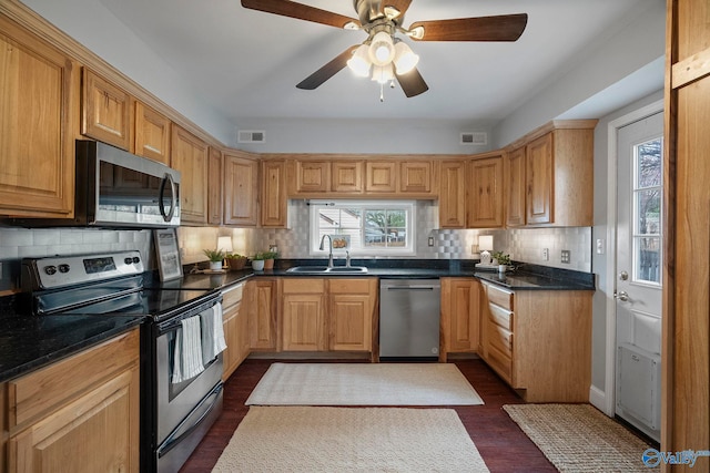 kitchen with a sink, stainless steel appliances, visible vents, dark wood-type flooring, and decorative backsplash