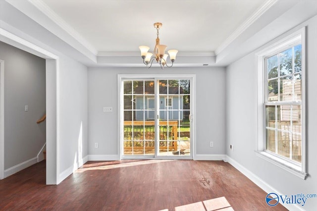 unfurnished dining area with ornamental molding, a chandelier, dark hardwood / wood-style flooring, and a tray ceiling