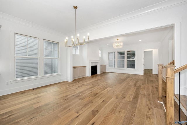 unfurnished living room with ornamental molding, a notable chandelier, and light hardwood / wood-style floors