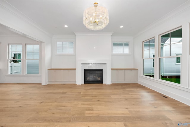 unfurnished living room with crown molding, a chandelier, and light hardwood / wood-style flooring