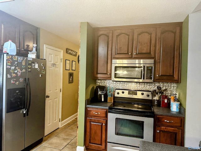 kitchen with light tile patterned flooring, stainless steel appliances, backsplash, and a textured ceiling