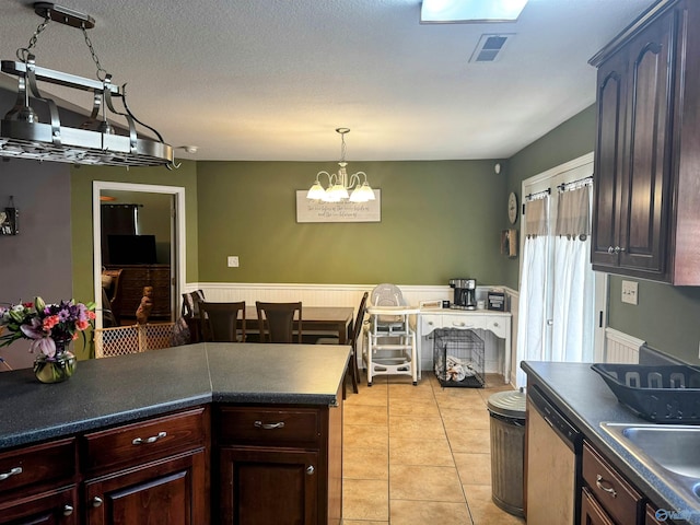 kitchen with light tile patterned flooring, dark brown cabinetry, dishwasher, and sink