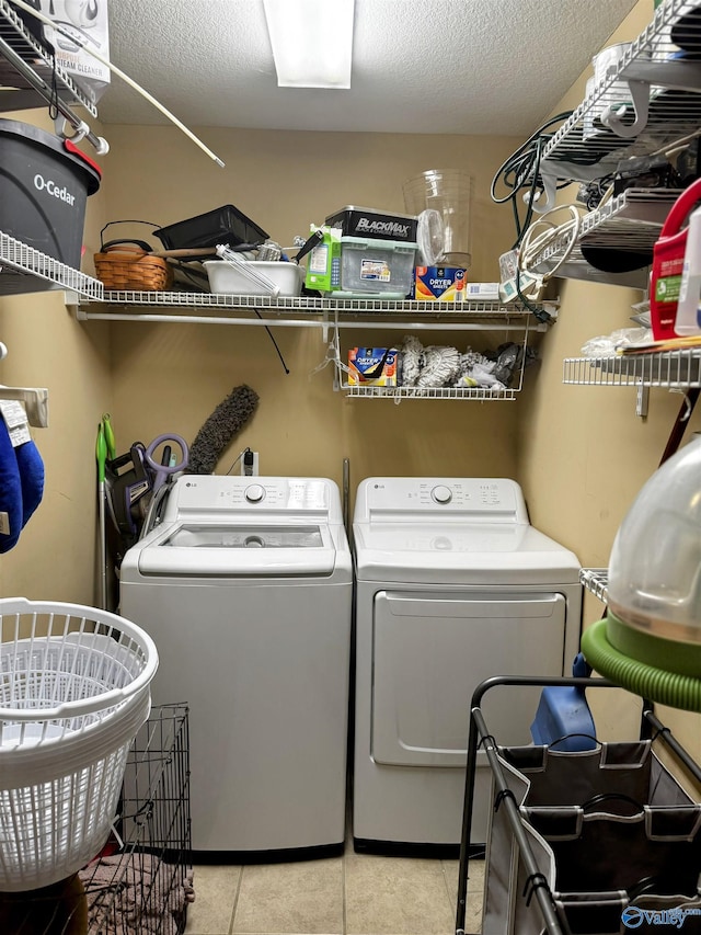 washroom featuring a textured ceiling, independent washer and dryer, and light tile patterned flooring