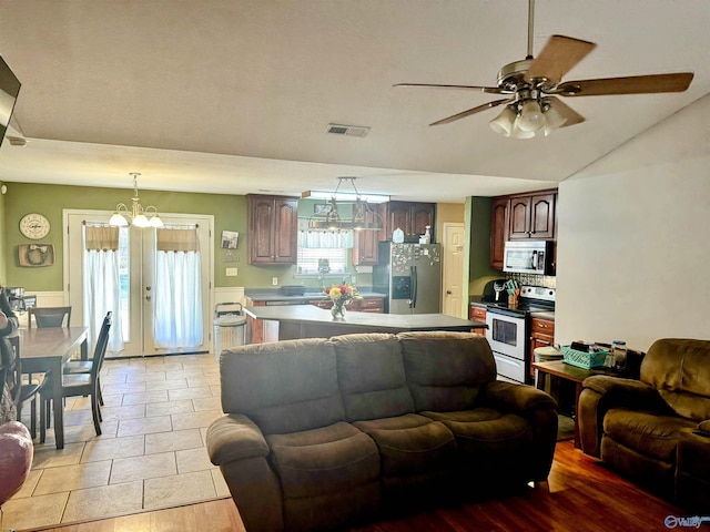 living room featuring ceiling fan with notable chandelier, french doors, and lofted ceiling