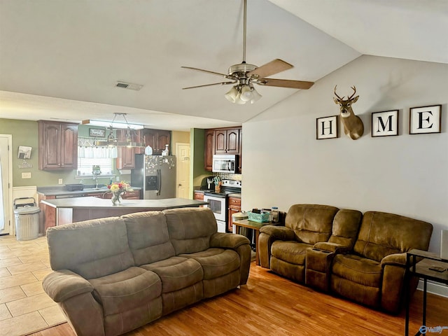 living room featuring sink, ceiling fan, light wood-type flooring, and vaulted ceiling