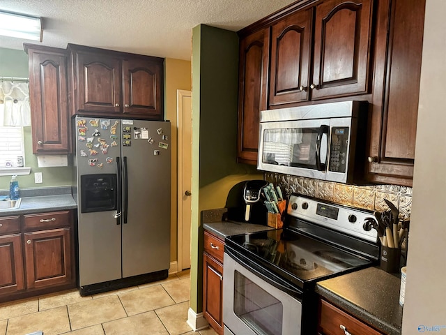 kitchen featuring appliances with stainless steel finishes, light tile patterned floors, and a textured ceiling