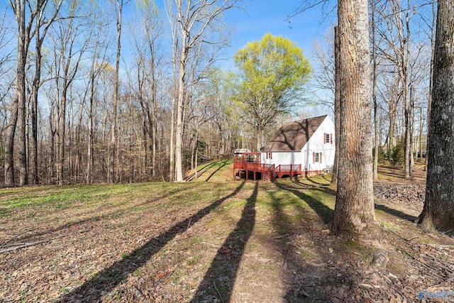 view of yard with a wooden deck and a wooded view