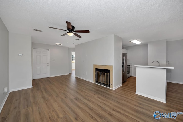 unfurnished living room with ceiling fan, dark hardwood / wood-style flooring, and a textured ceiling