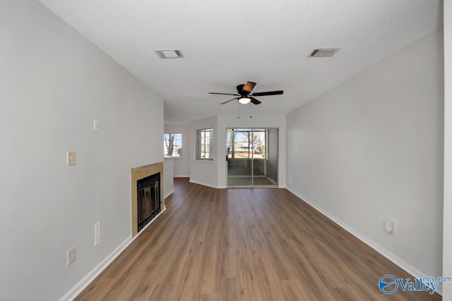 unfurnished living room with a textured ceiling, hardwood / wood-style flooring, and ceiling fan