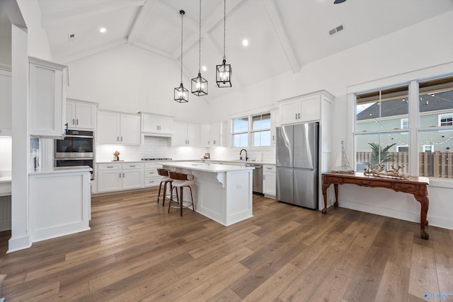 kitchen featuring stainless steel appliances, a center island, sink, and white cabinets