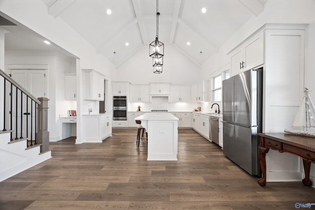 kitchen with sink, white cabinetry, hanging light fixtures, stainless steel appliances, and a kitchen island