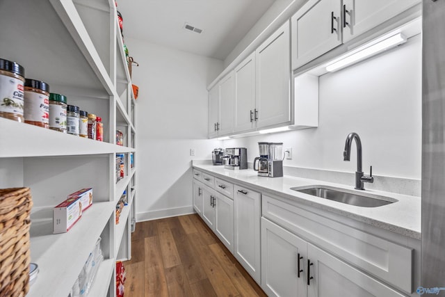 interior space with white cabinetry, dark wood-type flooring, sink, and light stone counters