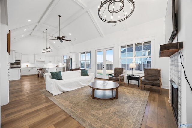 living room featuring dark hardwood / wood-style floors, ceiling fan with notable chandelier, high vaulted ceiling, beam ceiling, and french doors