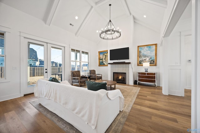 living room with beam ceiling, high vaulted ceiling, hardwood / wood-style flooring, and a tile fireplace