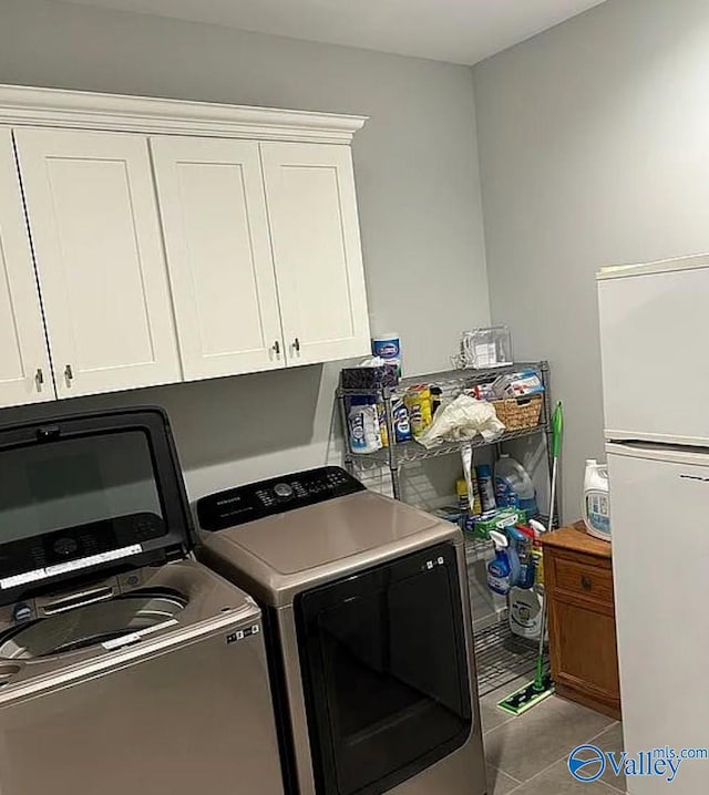 laundry area with tile patterned flooring, cabinets, and washing machine and clothes dryer