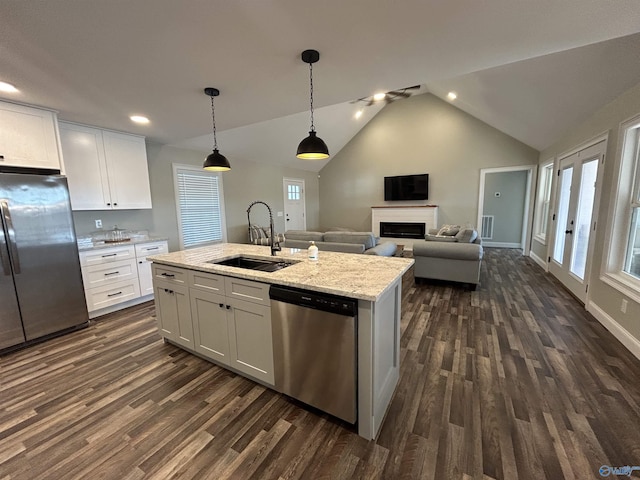 kitchen with sink, a center island with sink, hanging light fixtures, appliances with stainless steel finishes, and white cabinets