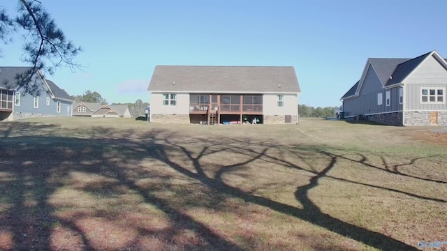 rear view of house featuring a sunroom and a lawn