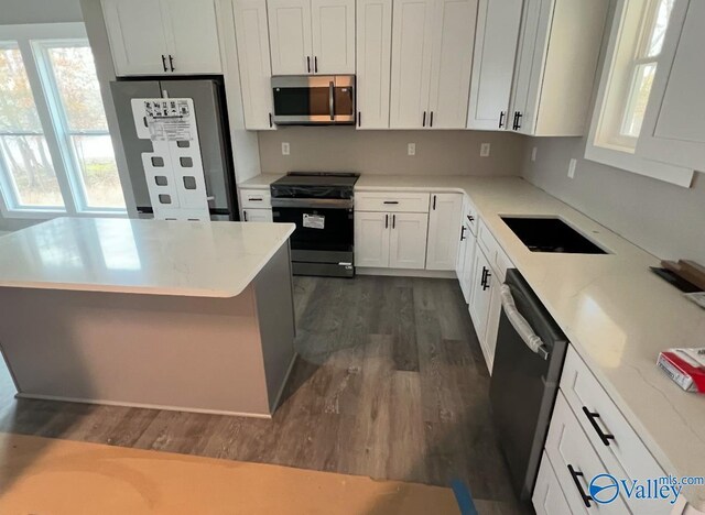 kitchen featuring stainless steel appliances, white cabinetry, dark hardwood / wood-style floors, and sink