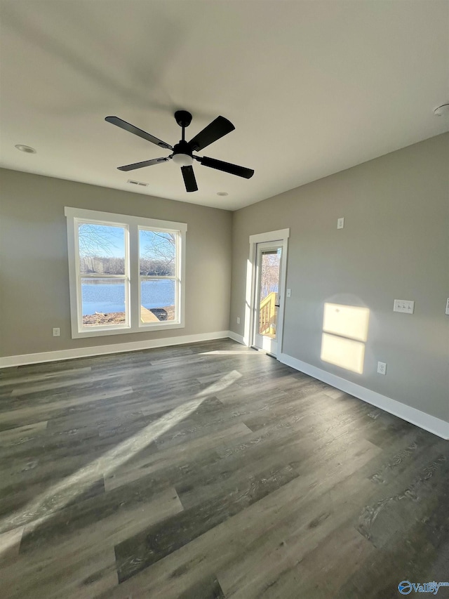 empty room featuring dark hardwood / wood-style floors, ceiling fan, and a water view